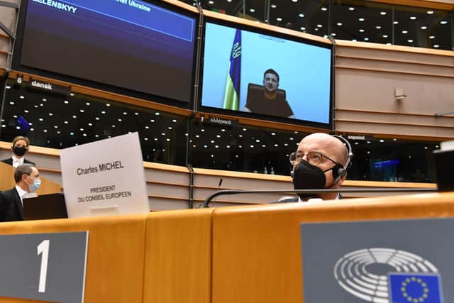 President of the European Council Charles Michel (R) listens to Ukrainian President Volodymyr Zelensky speaking in a video conference as he appears on a screen during a special plenary session of the European Parliament focused on the Russian invasion of Ukraine at the EU headquarters in Brussels,.
