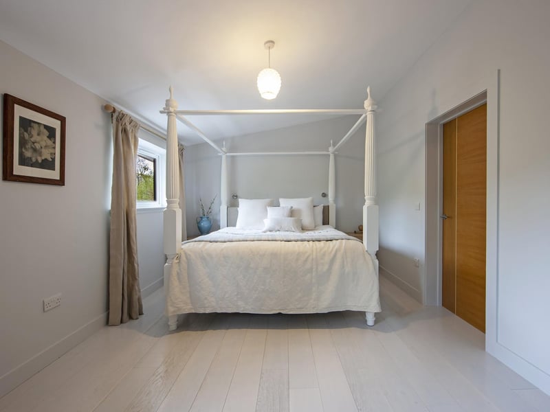 An elegant four-poster bed showcases the size of this double bedroom