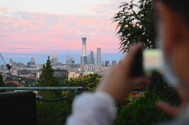 The China Zun tower is seen on the city skyline as people take pictures at a park during sunset in Beijing