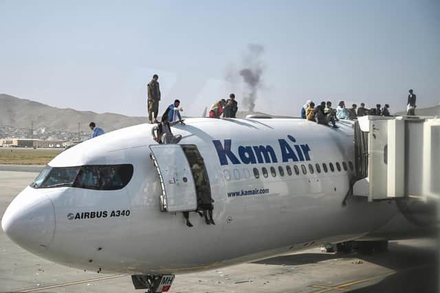 Afghan people climb atop a plane as they wait at the Kabul airport in Kabul. Picture: Wakil Kohsar/AFP via Getty Images