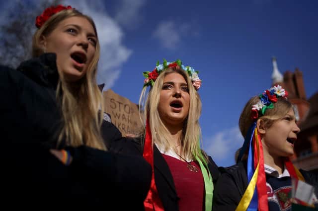 Three young protestors sing the Ukrainian national anthem outside the Russian Embassy in west London following the Russian invasion of Ukraine