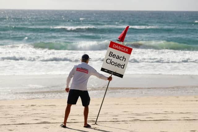 A Gold Coast Lifeguard erects a Beach Closed sign at Surfers Paradise in April 2020 (Photo: Chris Hyde/Getty Images)