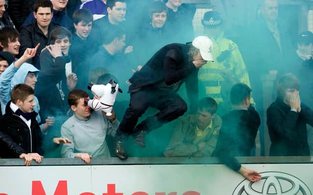 Falkirk fans try to escape flares let off by their supporters in a game with a Ross County in March 2012. (Photo by Sammy Turner/SNS Group).
