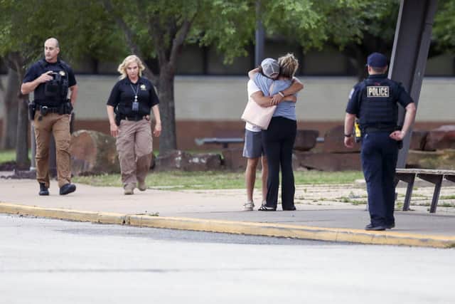 Two people hug outside at Memorial High School where people were evacuated from the scene of a shooting at the Natalie Medical Building.