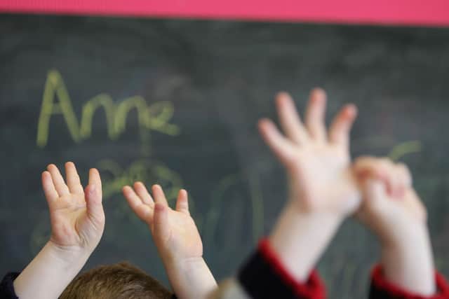 Children wave their hands at a school (Photo by Christopher Furlong/Getty Images)