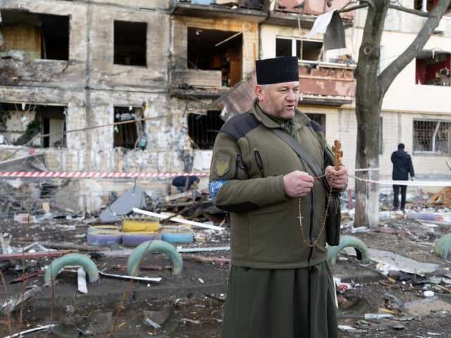 A Ukrainian military chaplain prays at the site of a fire caused by pieces of a fallen Russian missile in Kyiv's Obolon district.
Photojournalist Bennett Murray captured scenes on March 14 in Obolon district, Kyiv, Ukraine.