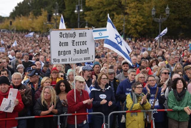 People gather under Israeli flags at a demonstration to show solidarity with Israel and against antisemitism in Berlin, Germany.