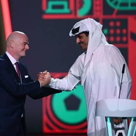 FIFA President Gianni Infantino (left) greets Qatar's Emir Sheikh Tamim bin Hamad al-Thani during the draw for the 2022 World Cup at the Doha Exhibition and Convention Center on April 1, 2022. (Photo by FRANCK FIFE/AFP via Getty Images)