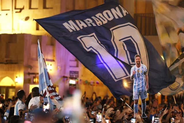 A Diego Maradona flag is seen next to a cardboard cutout of Lionel Messi.