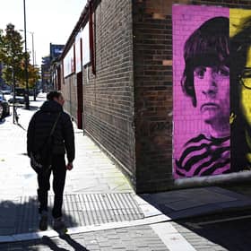 Pedestrians pass a mural depicting members of British rock band The Beatles (left-right) Ringo Starr, John Lennon, Paul McCartney and George Harrison on the side of a building in Liverpool. Picture: Paul Ellis/AFP via Getty Images