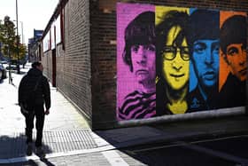 Pedestrians pass a mural depicting members of British rock band The Beatles (left-right) Ringo Starr, John Lennon, Paul McCartney and George Harrison on the side of a building in Liverpool. Picture: Paul Ellis/AFP via Getty Images