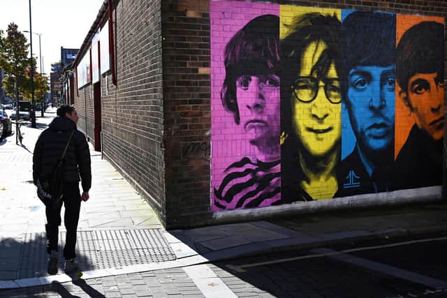 Pedestrians pass a mural depicting members of British rock band The Beatles (left-right) Ringo Starr, John Lennon, Paul McCartney and George Harrison on the side of a building in Liverpool. Picture: Paul Ellis/AFP via Getty Images