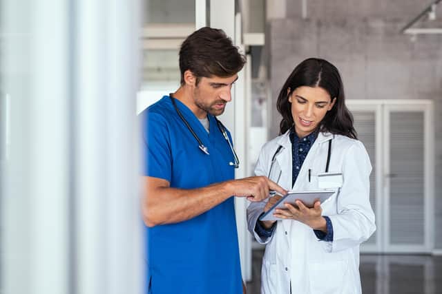 Doctor and nurse discussing over a medical report in hospital. Female mature doctor and nurse checking clinical report of patient online. Healthcare staff having discussion in a hallway of private clinic.