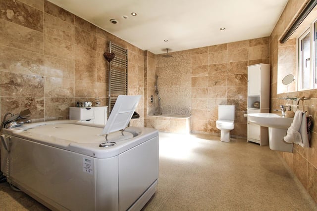 This spacious bathroom has a host of features including a stand-alone shower, fully tiled walls and a stand-alone bath tub.