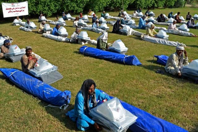 Flood-affected people sit along with their relief supplies being distributed by the International Federation of Red Cross in Jaffarabad district, Balochistan province.