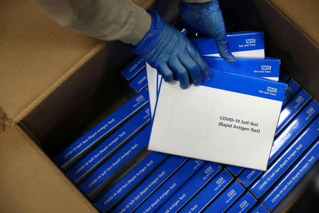 A health worker removes Covid-19 test kits from a box at a NHS Test and Trace Covid-19 testing unit. Photo by ADRIAN DENNIS/AFP via Getty Images