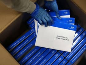 A health worker removes Covid-19 test kits from a box at a NHS Test and Trace Covid-19 testing unit. Photo by ADRIAN DENNIS/AFP via Getty Images