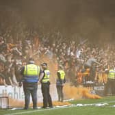 Dundee United fans throw a smoke bomb on the pitch during a cinch Premiership match against Ross County.