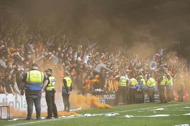Dundee United fans throw a smoke bomb on the pitch during a cinch Premiership match against Ross County.