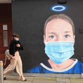 A woman walks past a mural in Manchester city centre.