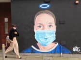 A woman walks past a mural in Manchester city centre.