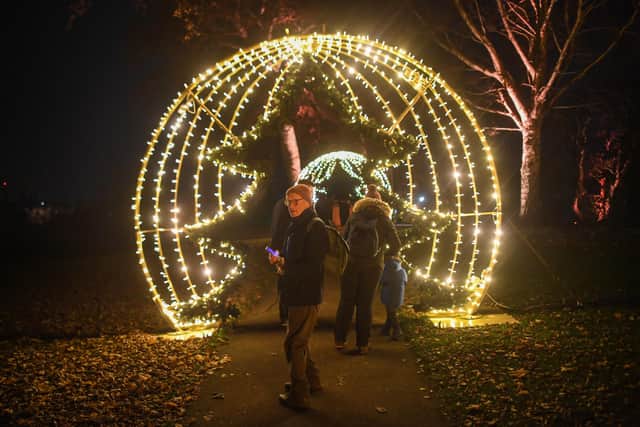 People are seen walking through a festive themed arch at the Royal Botanic Gardens Edinburgh on November 25, 2021 in Edinburgh, Scotland. Photo by Peter Summers/Getty Images