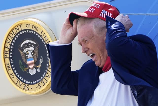 President Donald Trump holds his hat in the wind as he arrives on Air Force One at Selfridge Air National Guard Base in April.