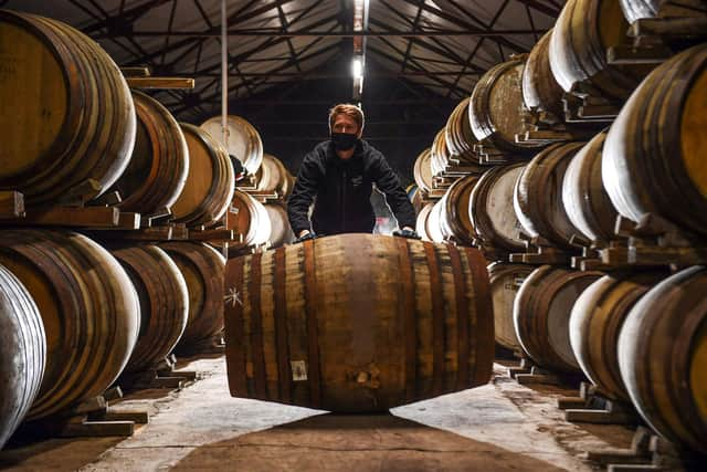 Employee Matthew Coulson poses for a photograph with whisky casks in the bonded warehouse at The Glenturret Distillery in Crieff, central Scotland, on February 26, 2021. - It has survived world wars, Prohibition and The Great Depression but this may very well be the toughest time yet for Scotland's oldest whisky maker. The Glenturret Distillery, located on the banks of the River Turret two miles (3.2 kilometres) northwest of the town of Crieff, was established in 1763 and is a popular stop for whisky enthusiasts. "It has been a really tough period for us with Covid, US tariffs and Brexit as well," the distillery's managing director, John Laurie, told AFP. (Photo by Andy Buchanan / AFP) / TO GO WITH AFP STORY BY Stuart GRAHAM (Photo by ANDY BUCHANAN/AFP via Getty Images)