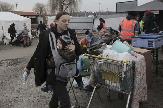 A woman carries her baby at border crossing, as refugees flee Russian invasion, in Medyka, Poland, Thursday, March 3, 2022. The U.N. refugee agency said Thursday at least 1 million people have fled Ukraine since Russia's invasion a week ago, an exodus without precedent in this century for its speed. (AP Photo/Visar Kryeziu)