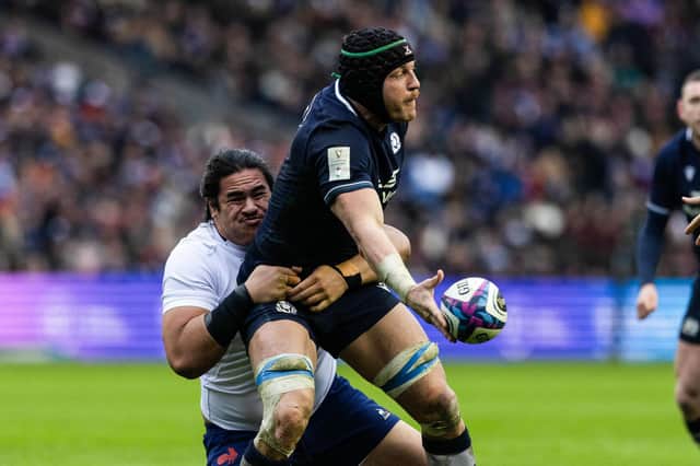Scotland's Jack Dempsey offloads against France under pressure from Posolo Tuilagi. (Photo by Craig Williamson / SNS Group)