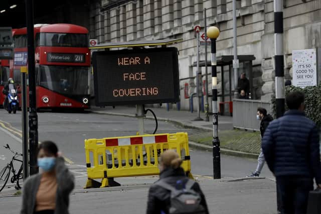 A sign is displayed outside Waterloo train station to remind people to wear face coverings