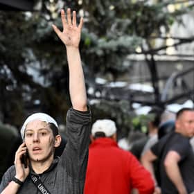 A wounded woman waves while speaking on the phone as rescuers and volunteers work to rescue people from under rubble after a Russian missile strike to a pizzeria in Kramatorsk. Picture: Genya Savilov/AFP via Getty Images