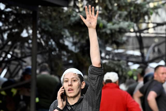 A wounded woman waves while speaking on the phone as rescuers and volunteers work to rescue people from under rubble after a Russian missile strike to a pizzeria in Kramatorsk. Picture: Genya Savilov/AFP via Getty Images