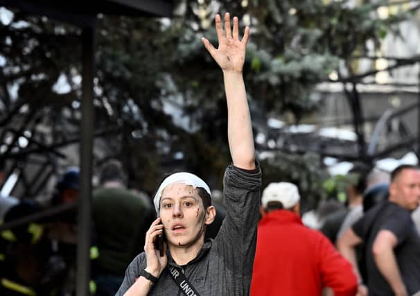 A wounded woman waves while speaking on the phone as rescuers and volunteers work to rescue people from under rubble after a Russian missile strike to a pizzeria in Kramatorsk. Picture: Genya Savilov/AFP via Getty Images