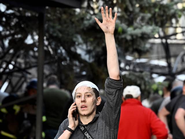 A wounded woman waves while speaking on the phone as rescuers and volunteers work to rescue people from under rubble after a Russian missile strike to a pizzeria in Kramatorsk. Picture: Genya Savilov/AFP via Getty Images
