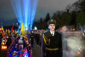 Ukrainian honour guards stand as a symbolic illumination called "Ray of Memory" is seen over the graves of Ukrainian soldiers, who died in the war with Russia, at Lychakiv Cemetery in Lviv (Photo by YURIY DYACHYSHYN/AFP via Getty Images)