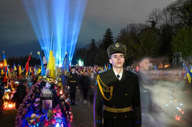 Ukrainian honour guards stand as a symbolic illumination called "Ray of Memory" is seen over the graves of Ukrainian soldiers, who died in the war with Russia, at Lychakiv Cemetery in Lviv (Photo by YURIY DYACHYSHYN/AFP via Getty Images)