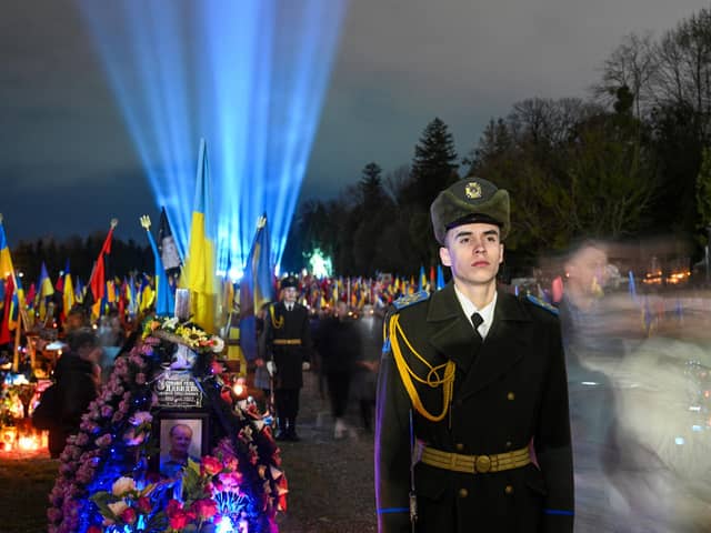 Ukrainian honour guards stand as a symbolic illumination called "Ray of Memory" is seen over the graves of Ukrainian soldiers, who died in the war with Russia, at Lychakiv Cemetery in Lviv (Photo by YURIY DYACHYSHYN/AFP via Getty Images)