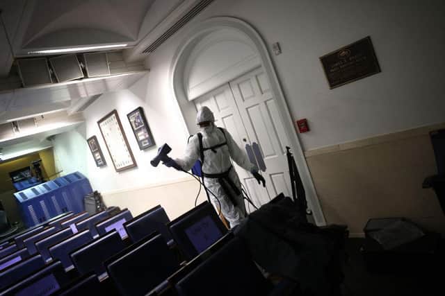 A member of the White House cleaning staff sanitizes the James S. Brady Press Briefing Room yesterday. U.S. President Trump, several members of his staff, and three members of the press corps have recently tested positive for coronavirus. (Photo by Win McNamee/Getty Images)