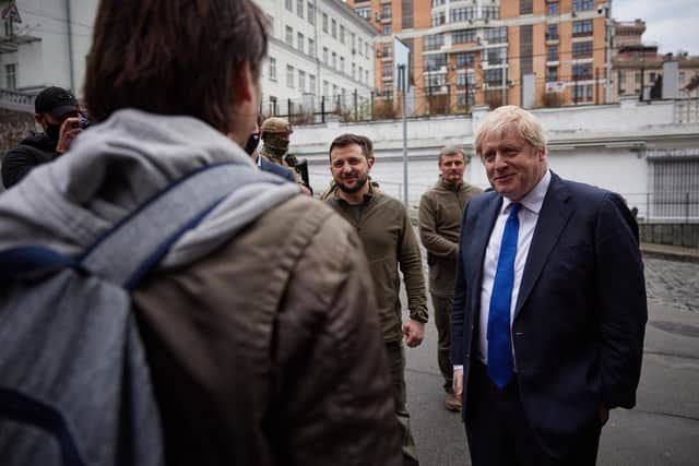 A handout photo released by the Ukrainian Presidential Press Service shows British Prime Minister Boris Johnson (R) speaking to a local resident as he walks with Ukrainian President Volodymyr Zelensky (C) in central Kyiv on April 9, 2022. (Photo by Stringer / UKRAINIAN PRESIDENTIAL PRESS SERVICE / AFP)