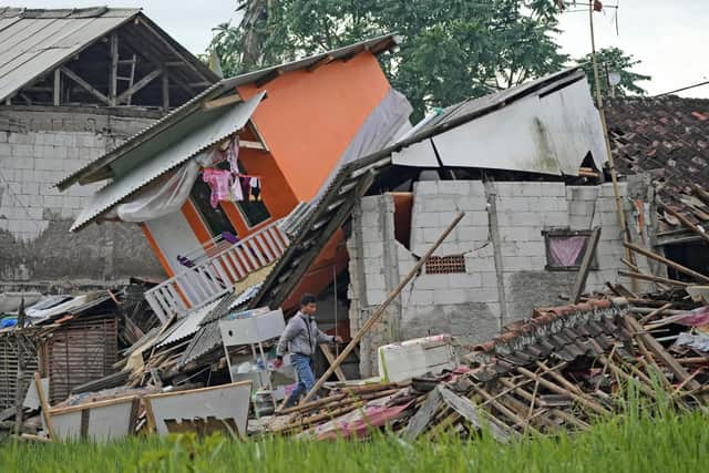 A man makes his way past ruins of earthquake-damaged houses in Cianjur, West Java, Indonesia Tuesday, Nov. 22, 2022. The earthquake has toppled buildings on Indonesia's densely populated main island, killing a number of people and injuring hundreds. (AP Photo/Tatan Syuflana)