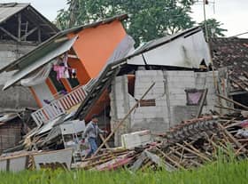 A man makes his way past ruins of earthquake-damaged houses in Cianjur, West Java, Indonesia Tuesday, Nov. 22, 2022. The earthquake has toppled buildings on Indonesia's densely populated main island, killing a number of people and injuring hundreds. (AP Photo/Tatan Syuflana)