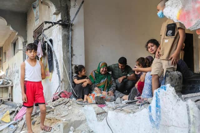 A woman is consoled as people search through buildings that were destroyed during Israeli air raids in the southern Gaza Strip in Khan Yunis, Gaza. Two weeks after a deadly Hamas attack in southern Israel that sparked a retaliatory siege of Gaza, in which thousands have died and hundreds of thousands have been displaced, aid trucks have started entering the Palestinian territory via Egypt carrying food, water and medicines. The UN agency UNRWA, or the Relief and Works Agency for Palestine Refugees, says the initial aid is a "drop in the ocean" of what is needed. (Photo by Ahmad Hasaballah/Getty Images)
