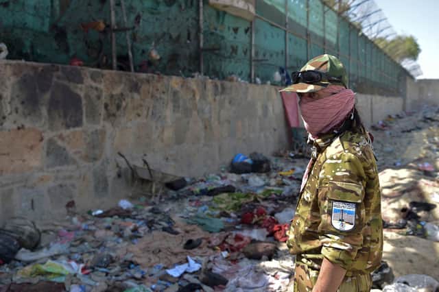 A Taliban fighter stands guard at the site of the August 26 twin suicide bombs, which killed scores of people including 13 US troops, at Kabul airport