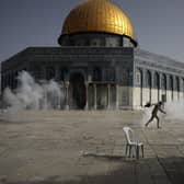 A Palestinian man runs away from tear gas during clashes with Israeli security forces in front of the Dome of the Rock Mosque in Jerusalem (Picture: Mahmoud Illean/AP)
