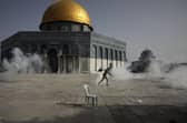 A Palestinian man runs away from tear gas during clashes with Israeli security forces in front of the Dome of the Rock Mosque in Jerusalem (Picture: Mahmoud Illean/AP)