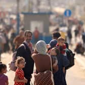 A Palestinian woman gives water to her child as families fleeing Gaza City and other parts of northern Gaza towards the southern areas, walk along a main road.