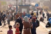 A Palestinian woman gives water to her child as families fleeing Gaza City and other parts of northern Gaza towards the southern areas, walk along a main road.