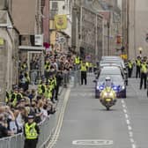 The hearse carrying the coffin of Queen Elizabeth II, draped with the Royal Standard of Scotland, passing along the Royal Mile, Edinburgh, as it continued its journey to the Palace of Holyroodhouse from Balmoral