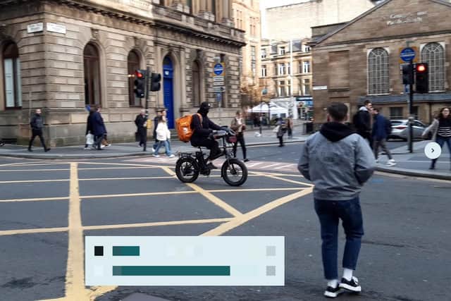 A delivery rider going through red lights while pedestrians cross the road in Glasgow city centre on Friday. (Photo by The Scotsman)